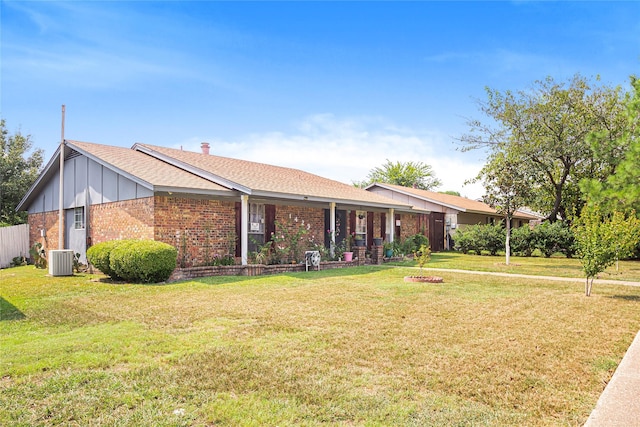 ranch-style home with central AC unit, a front lawn, brick siding, board and batten siding, and roof with shingles