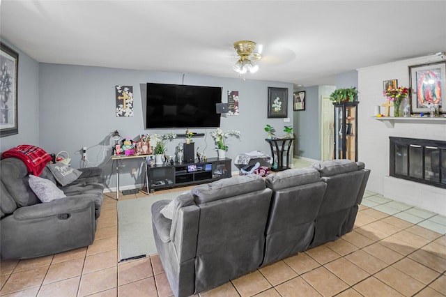 living area with light tile patterned floors, a ceiling fan, and a fireplace