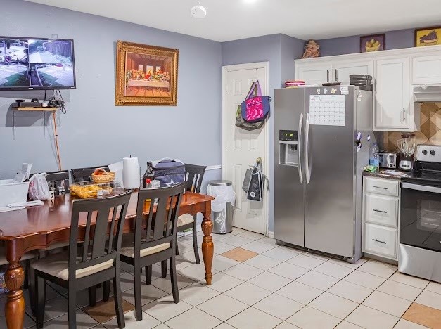 kitchen featuring white cabinets, stainless steel appliances, range hood, and light tile patterned floors