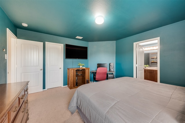 carpeted bedroom featuring a textured ceiling and ensuite bathroom