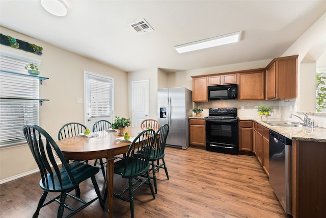 kitchen featuring a wealth of natural light, sink, black appliances, and hardwood / wood-style floors