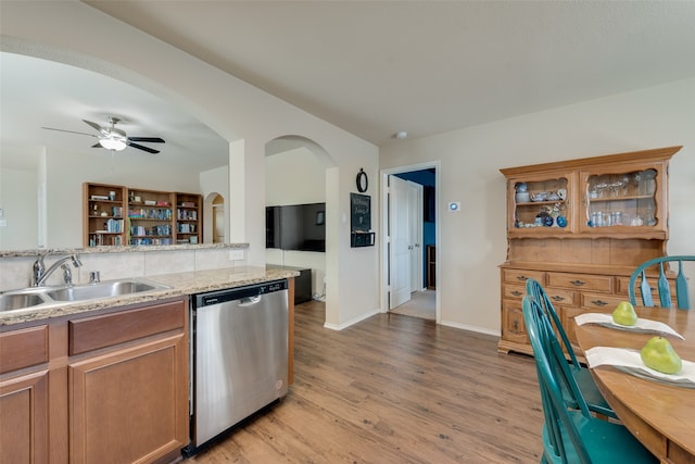 kitchen featuring light stone countertops, sink, dishwasher, light wood-type flooring, and ceiling fan