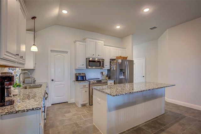 kitchen with lofted ceiling, sink, light stone counters, white cabinetry, and stainless steel appliances