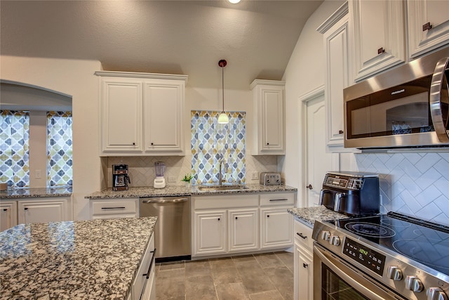 kitchen featuring appliances with stainless steel finishes, backsplash, sink, white cabinets, and lofted ceiling