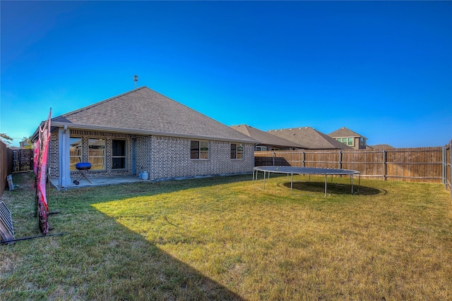 4035 Three Forks Rd, Kaufman, TX 75142 - rear view of house featuring a trampoline, a shingled roof, and brick siding