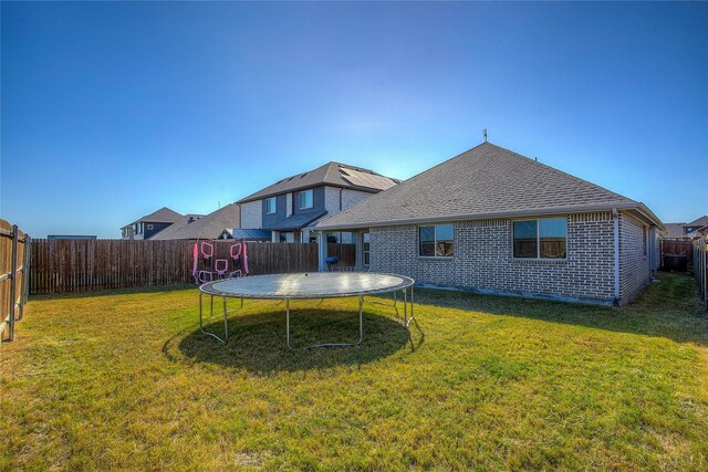 4035 Three Forks Rd, Kaufman, TX 75142 - rear view of property with a trampoline, a shingled roof, and brick siding