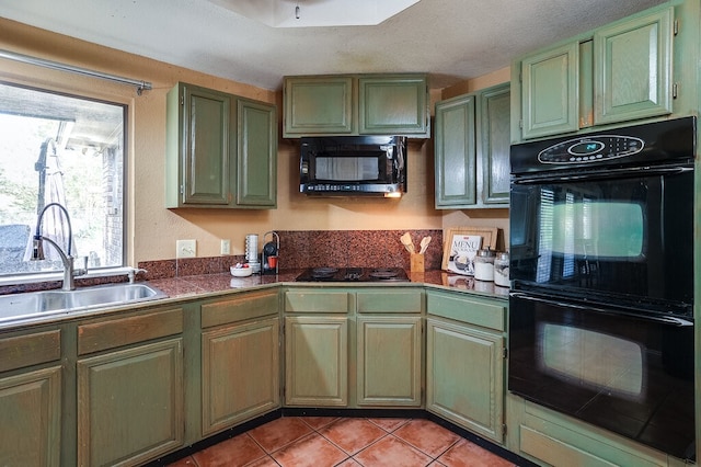 kitchen featuring sink, black appliances, green cabinets, and light tile patterned floors