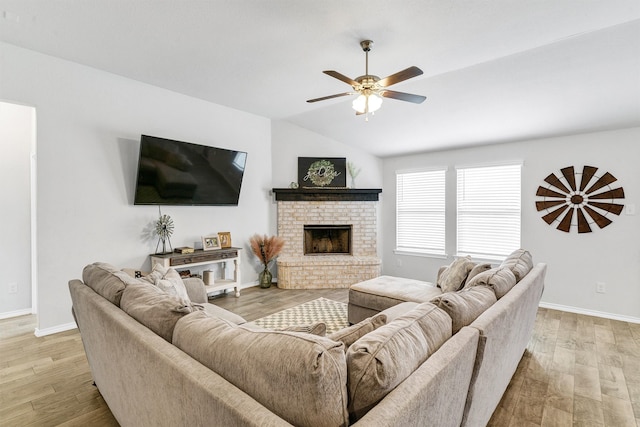 living room with light wood-type flooring, lofted ceiling, ceiling fan, and a brick fireplace