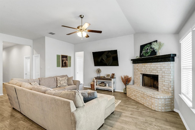 living room featuring a fireplace, ceiling fan, light wood-type flooring, and lofted ceiling