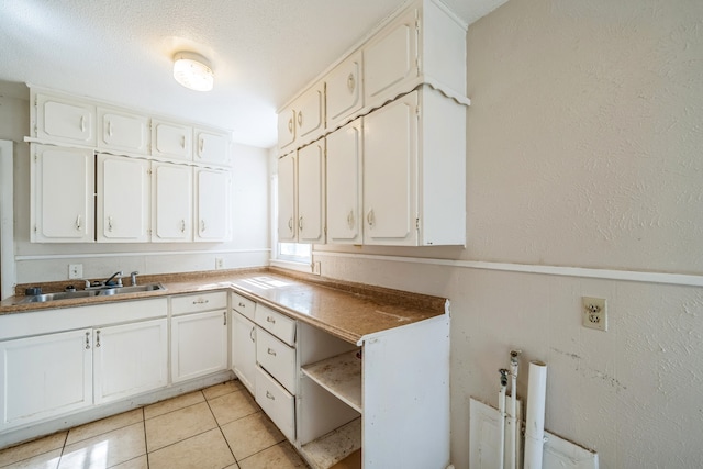 kitchen with sink, white cabinetry, a textured ceiling, and light tile patterned floors