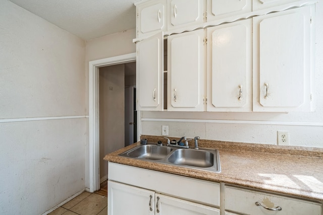 kitchen with sink, white cabinetry, and light tile patterned flooring