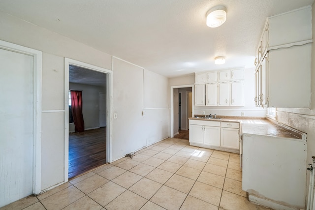 kitchen featuring sink, white cabinets, a textured ceiling, and light hardwood / wood-style floors