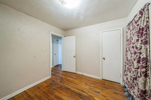 unfurnished bedroom with a textured ceiling and dark hardwood / wood-style floors