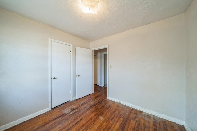 unfurnished bedroom with a textured ceiling and dark wood-type flooring