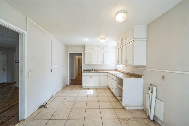 kitchen with white cabinetry, light tile patterned flooring, and sink