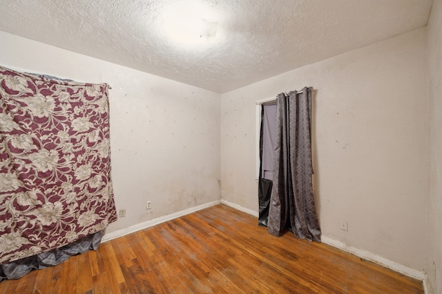 unfurnished room with hardwood / wood-style floors and a textured ceiling