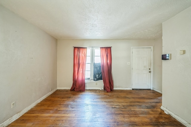 spare room featuring a textured ceiling and dark hardwood / wood-style flooring