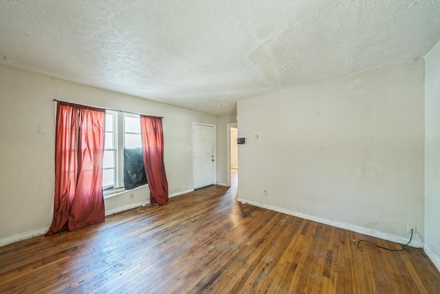 unfurnished room featuring dark wood-type flooring and a textured ceiling