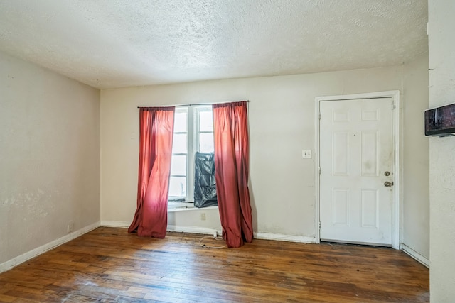 unfurnished room with a textured ceiling and dark wood-type flooring