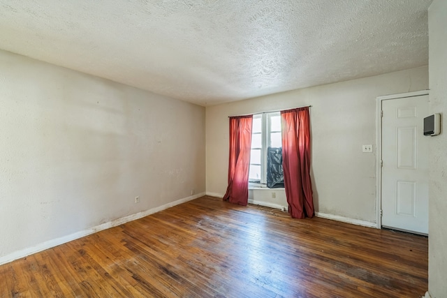 empty room with dark hardwood / wood-style floors and a textured ceiling