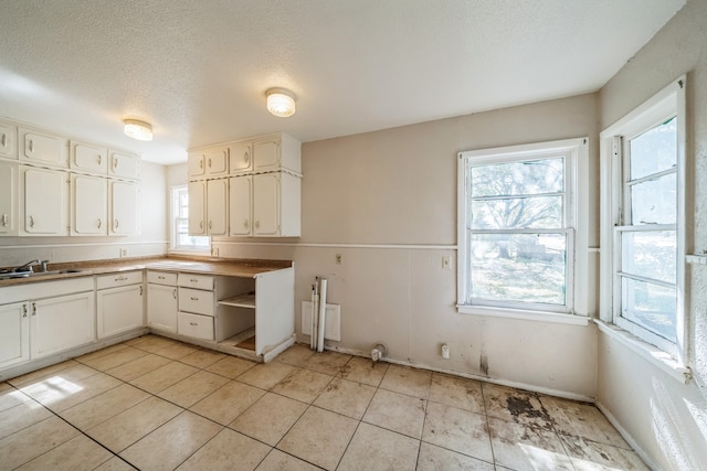 kitchen featuring sink, white cabinetry, a textured ceiling, and light tile patterned flooring