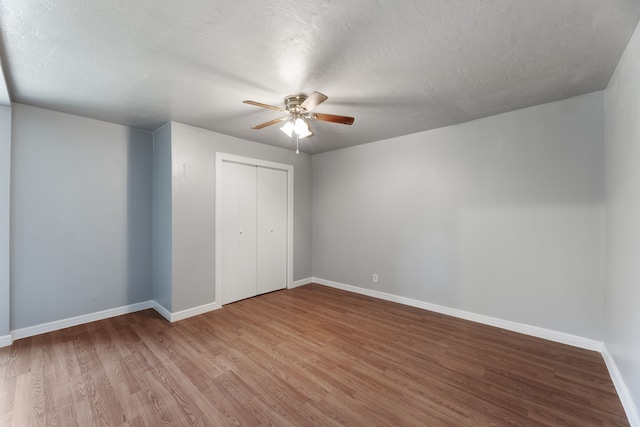 unfurnished bedroom with a textured ceiling, hardwood / wood-style flooring, a closet, and ceiling fan