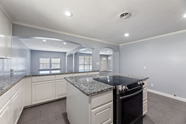 kitchen with stone counters, a center island, electric range, white cabinets, and ornamental molding