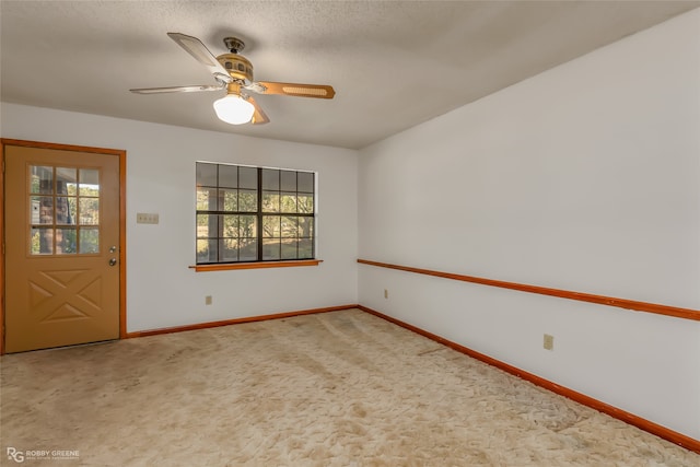 carpeted empty room with a wealth of natural light, a textured ceiling, and ceiling fan