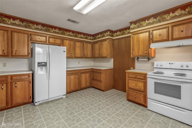 kitchen featuring a textured ceiling and white appliances