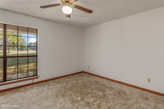 carpeted spare room featuring a textured ceiling and ceiling fan