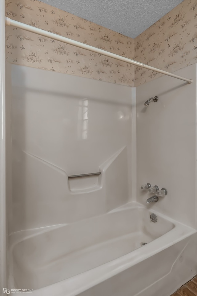 bathroom with shower / washtub combination, a textured ceiling, and hardwood / wood-style flooring