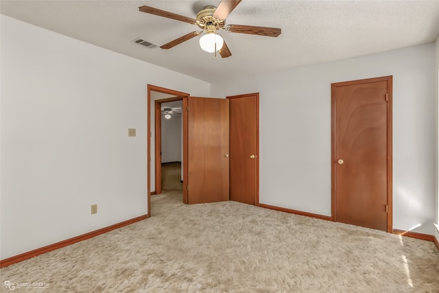 unfurnished bedroom featuring ceiling fan, a textured ceiling, and light colored carpet