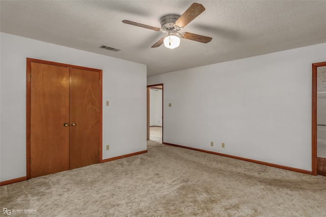 unfurnished bedroom featuring a textured ceiling, light colored carpet, and ceiling fan