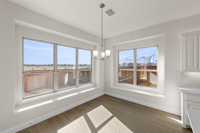 unfurnished dining area featuring dark hardwood / wood-style floors and a chandelier