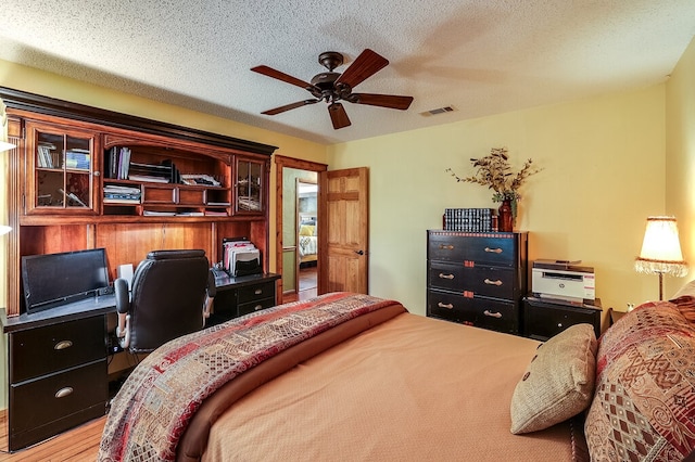 bedroom featuring a textured ceiling, light wood-type flooring, and ceiling fan