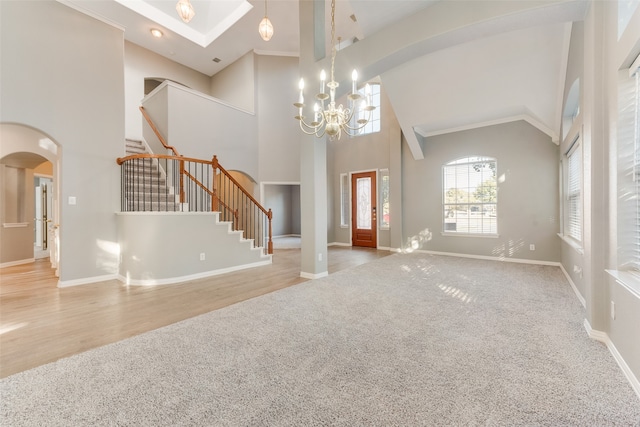 interior space featuring light hardwood / wood-style floors, high vaulted ceiling, ornamental molding, and an inviting chandelier