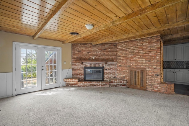 unfurnished living room with carpet flooring, a fireplace, french doors, and beamed ceiling