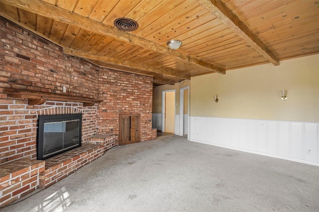 unfurnished living room featuring a fireplace, carpet flooring, beamed ceiling, and wood ceiling