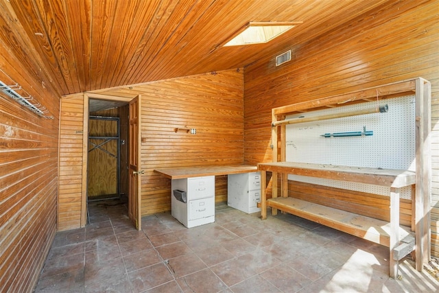 interior space featuring a workshop area, lofted ceiling with skylight, wood ceiling, and wood walls