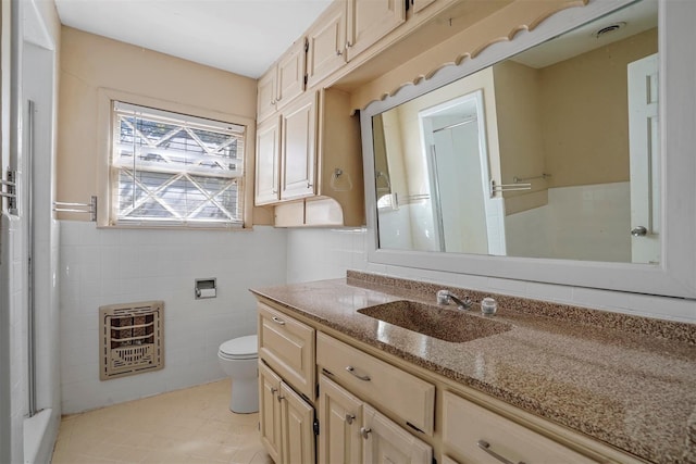 bathroom with vanity, tile patterned flooring, toilet, tile walls, and heating unit