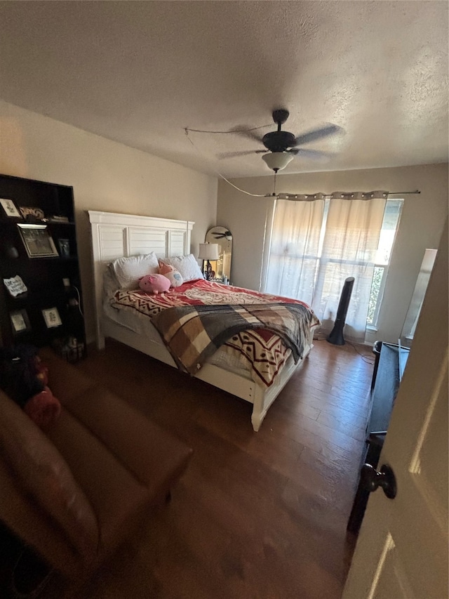 bedroom with a textured ceiling, wood-type flooring, and ceiling fan