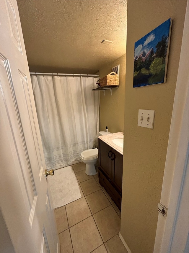 bathroom with vanity, a textured ceiling, toilet, and tile patterned flooring