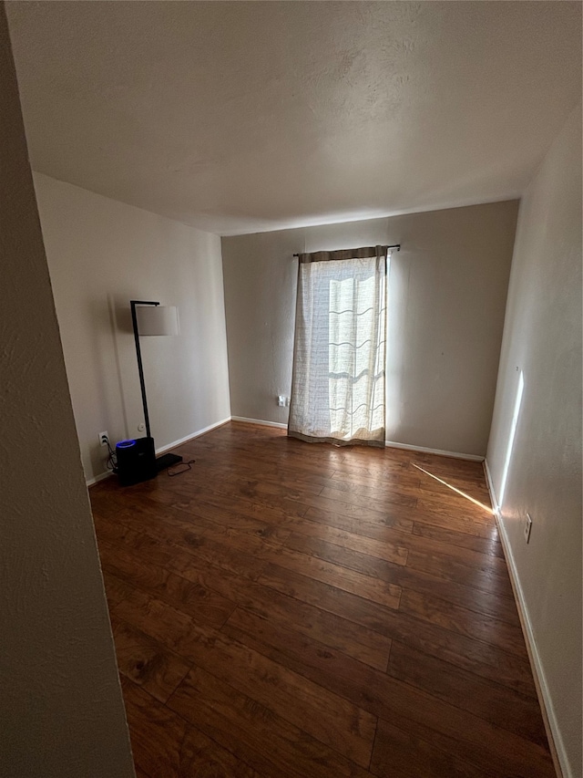 spare room with a textured ceiling and dark hardwood / wood-style flooring