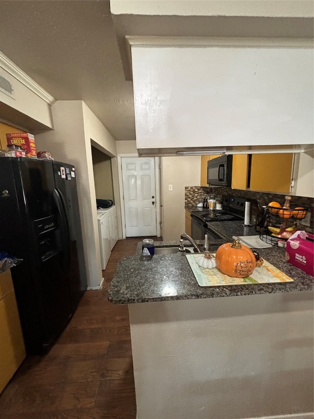 kitchen with kitchen peninsula, backsplash, black appliances, dark wood-type flooring, and washer and clothes dryer