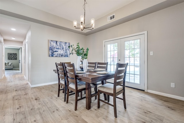 dining area with light hardwood / wood-style flooring, french doors, and an inviting chandelier