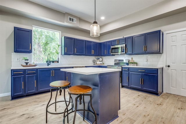 kitchen with appliances with stainless steel finishes, blue cabinets, and a breakfast bar area