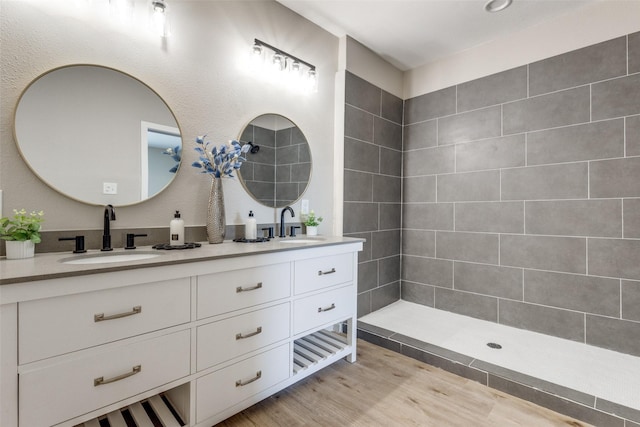 bathroom featuring vanity, a tile shower, and wood-type flooring