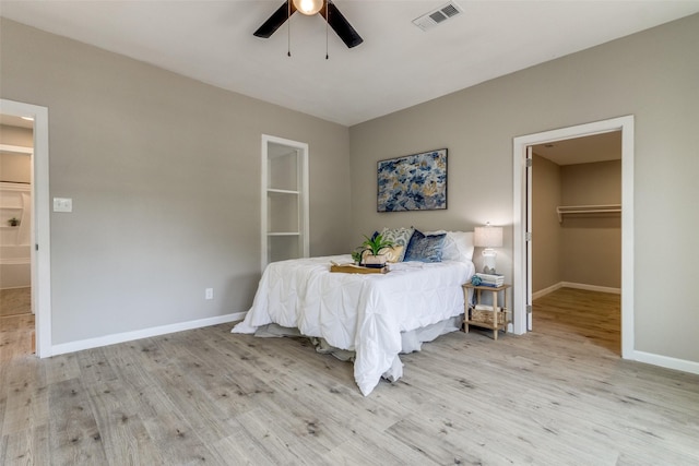 bedroom with light wood-type flooring, a closet, ceiling fan, and a spacious closet