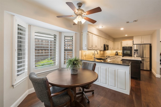 kitchen with kitchen peninsula, tasteful backsplash, sink, black appliances, and white cabinetry