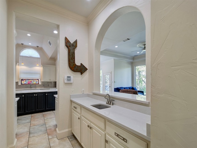 kitchen with ornamental molding, ceiling fan, sink, and backsplash